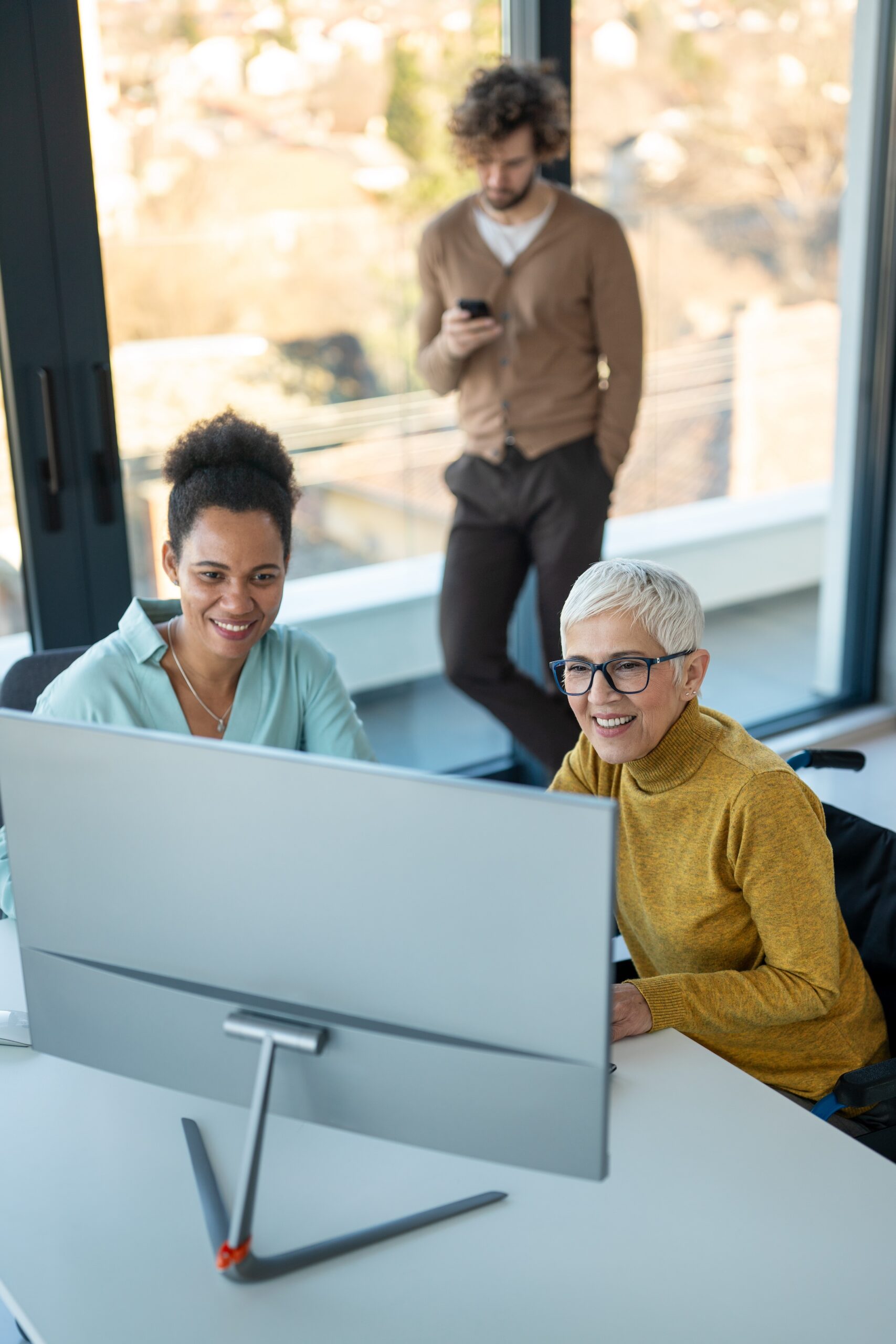 Business woman in wheelchair working with colleague in modern inclusive office. Diversity, support